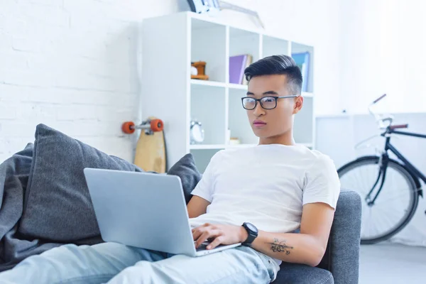 Stilig Ung Asiatisk Man Använder Laptop Soffan Hemma — Gratis stockfoto