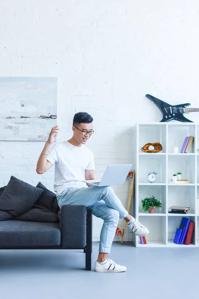 Animado Bonito Asiático Homem Usando Laptop Sofá Gestos Sala Estar — Fotografia de Stock