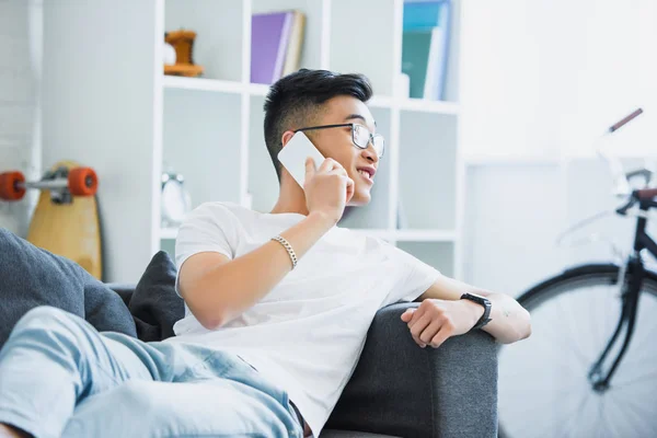 Koltukta Yalan Yanında Smartphone Oturma Odasında Konuşurken Asya Yakışıklı — Stok fotoğraf