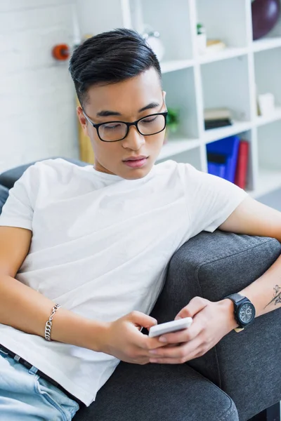 Guapo Asiático Hombre Gafas Acostado Sofá Uso Teléfono Inteligente Casa — Foto de stock gratis