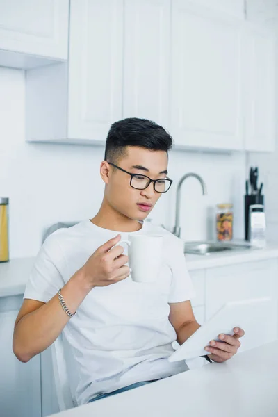 Young Asian Man Eyeglasses Holding Cup Using Digital Tablet — Free Stock Photo