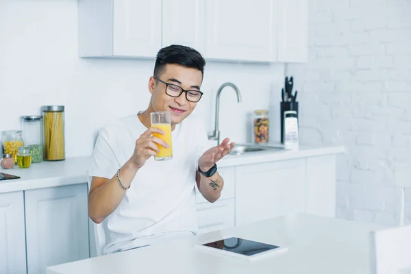 Щасливий Молодий Азіатський Чоловік Окулярах Тримає Склянку Соку Використовує Цифровий — Безкоштовне стокове фото