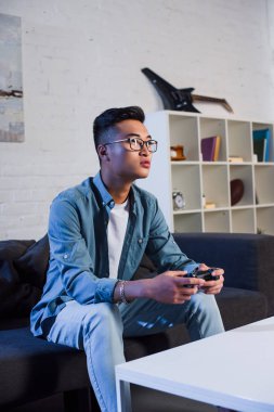 joystick kullanarak ve video oyun evde oynarken Genç Asyalı adam 
