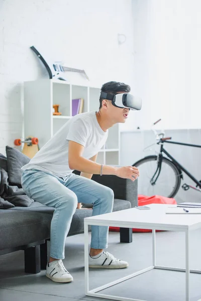 Emocional Joven Asiático Hombre Usando Virtual Realidad Auricular Casa — Foto de stock gratis