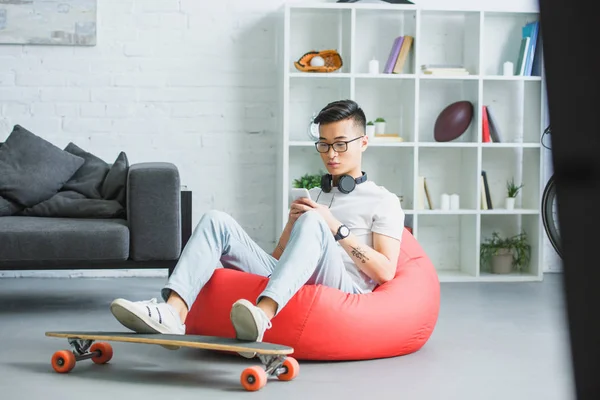 Fasulye Çanta Sandalyede Oturan Evde Smartphone Kullanarak Asya Yakışıklı Genç — Stok fotoğraf