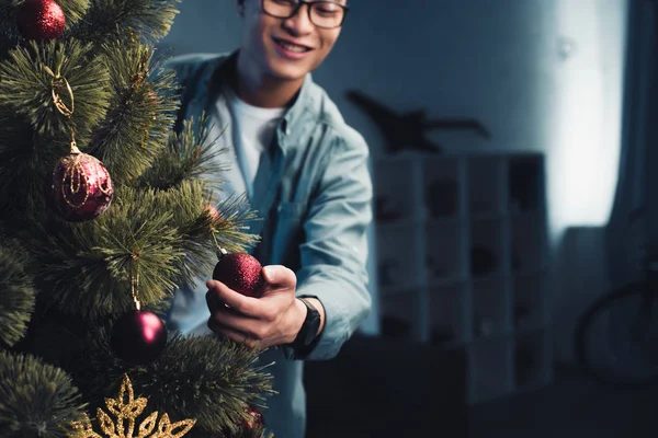 在家里装饰圣诞树的快乐年轻亚裔男子裁剪拍摄 — 图库照片