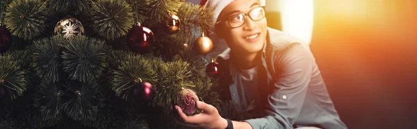 Hezký Šťastný Asijský Mladík Santa Čepici Brýle Zdobení Vánočního Stromu — Stock fotografie