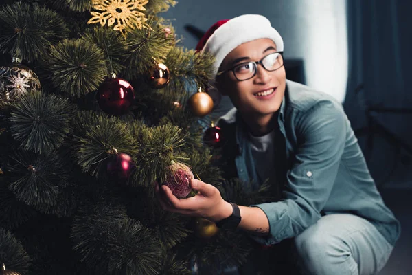 Young Happy Asian Man Santa Hat Decorating Christmas Tree Looking — Free Stock Photo