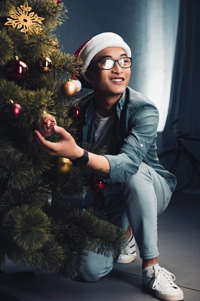 Sorrindo Asiático Homem Santa Chapéu Decoração Natal Árvore Olhando Para — Fotos gratuitas