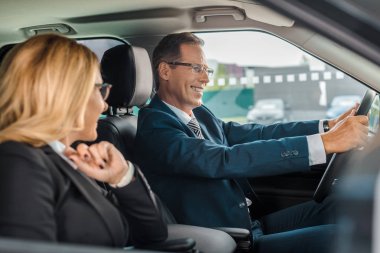 smiling business couple sitting in new car for test drive clipart