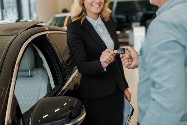 kadın araba satıcısı showroom, arabanın anahtarını alarak adam resmini kırpılmış