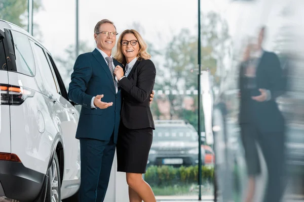 微笑的商业夫妇寻找新的汽车在经销商沙龙 — 免费的图库照片