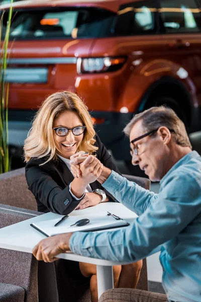 Adult Man Female Car Dealer Arm Wrestling Showroom — Free Stock Photo