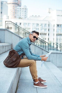 gazete tutan ve kameraya bakarak güneş gözlüğü şık adam yan görünüm