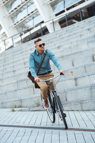 stylish middle aged man in sunglasses riding bicycle on street 