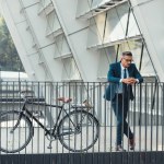 Réussi homme d'affaires d'âge moyen dans l'usure formelle penché à balustrade près de vélo