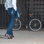 Recortado disparo de hombre de negocios en ropa formal va a bicicleta estacionado en la calle