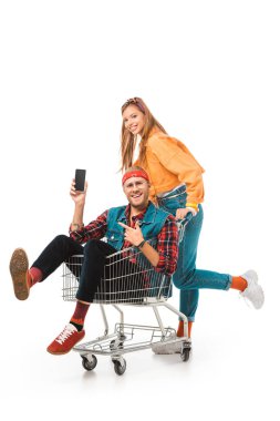 alışveriş sepeti smartphone ile boş perde arkasında, onun kız arkadaşı üzerinde beyaz izole iken işaret içinde şık erkek hipster