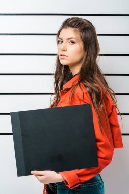 arrested young woman posing with empty prison board in front of police line up clipart