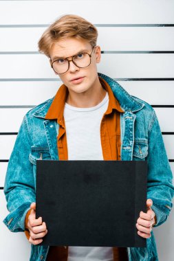 yakışıklı hipster holding boş hapishane kurulu polis hattı önünde dururken