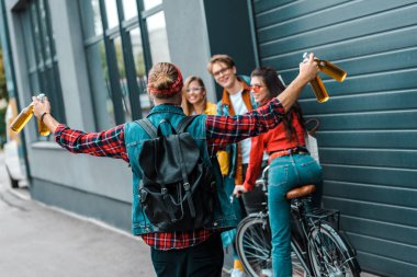 excited male hipster brought beer to happy friends on street with bicycle clipart