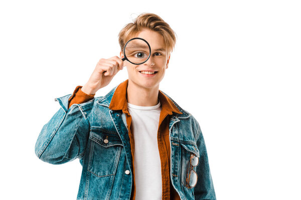 happy young hipster man in denim jacket having fun with magnifier isolated on white