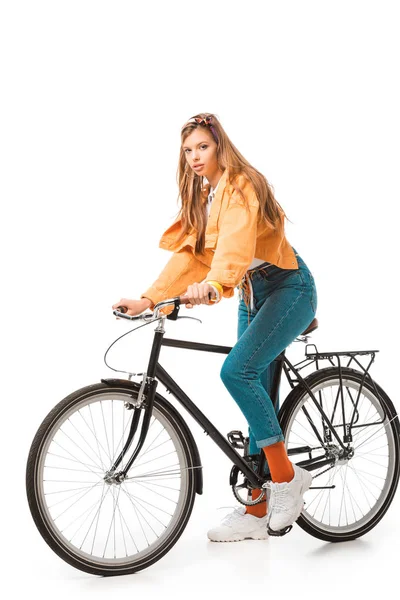 时髦的女孩坐在自行车上 看着在白色的相机隔离 — 图库照片