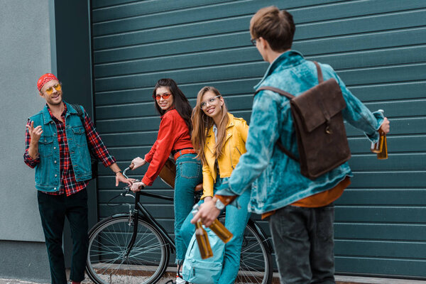 hipster brought bottles of beer to happy friends on street with bicycle