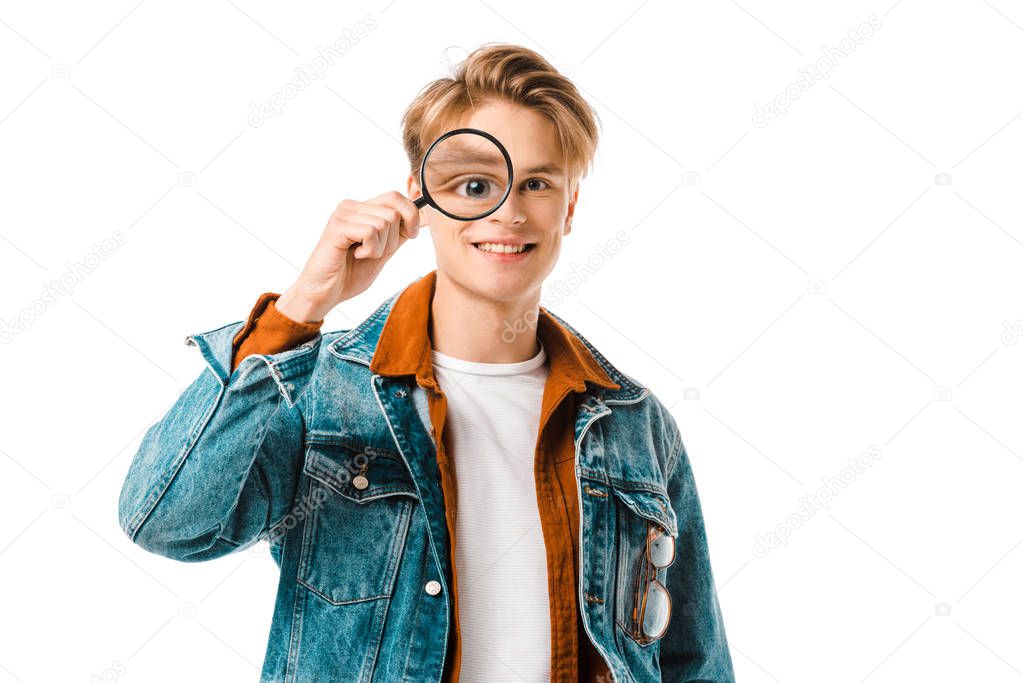 happy young hipster man in denim jacket having fun with magnifier isolated on white