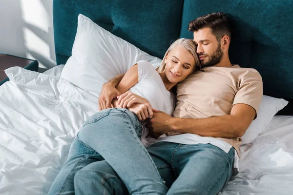 一对年轻夫妇抱着睡在床上的卧室 — 图库照片