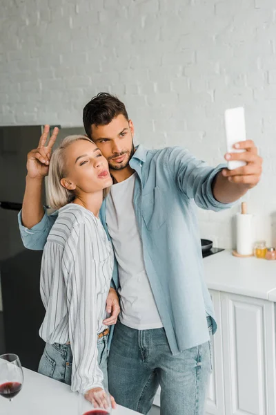 Junges Paar Grimassiert Und Macht Selfie Mit Smartphone Küche — kostenloses Stockfoto
