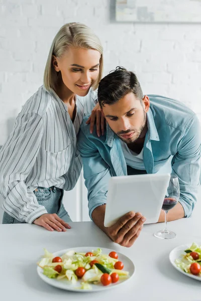 Jeune Couple Utilisant Tablette Dans Cuisine Salade Sur Table — Photo gratuite