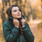 Избирательный фокус красивой молодой женщины в куртке, позирующей на открытом воздухе Избирательный фокус красивой молодой женщины в куртке, позирующей на открытом воздухе