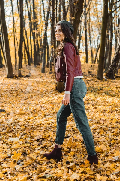 秋の公園を歩いてベレー帽と革のジャケットで魅力的なスタイリッシュな女性  — 無料ストックフォト