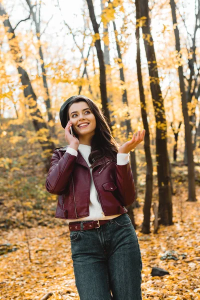 皮革夹克的快乐女孩的低角度看在秋季公园用手在智能手机和手势上交谈 — 图库照片