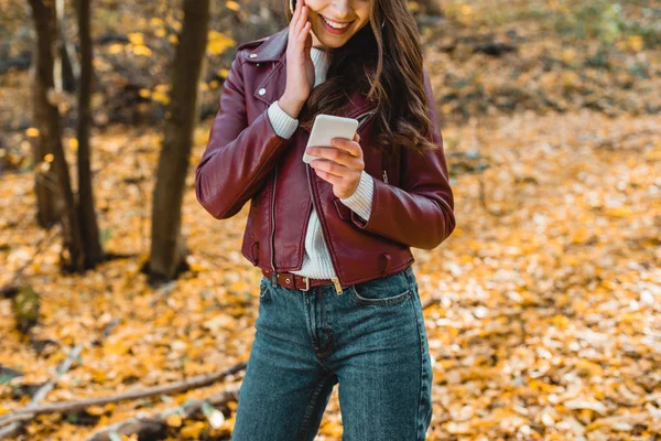 Beskuren Bild Leende Kvinna Snygg Skinnjacka Med Smartphone Höstlig Skog — Stockfoto