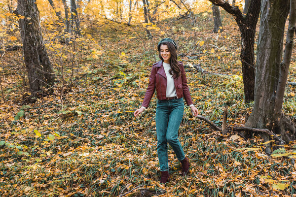 модная молодая женщина в кожаной куртке и берете прогуливаясь по осеннему парку

