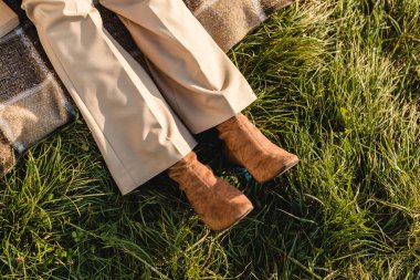 low section of female legs in suede brown shoes on grass outdoors  clipart
