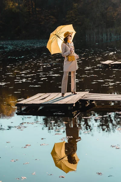 Модная Женщина Солнцезащитных Очках Плащ Шляпа Позируют Желтым Зонтиком Возле — стоковое фото