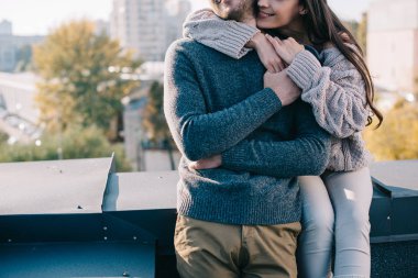 cropped shot of young couple embracing on rooftop clipart
