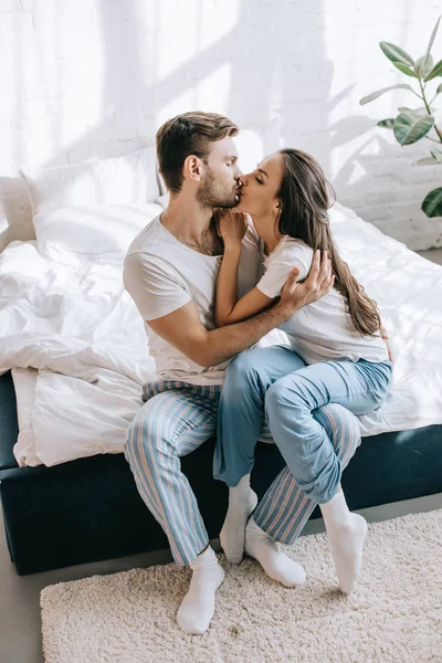 Belo Jovem Casal Pijama Beijando Enquanto Sentado Cama Manhã — Fotografia de Stock