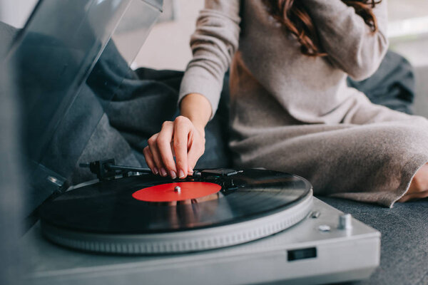cropped shot of woman listening music with vinyl record player on couch at home