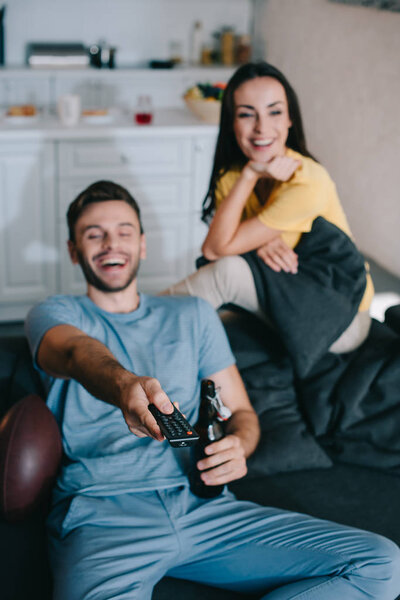 happy young couple watching american football game at home