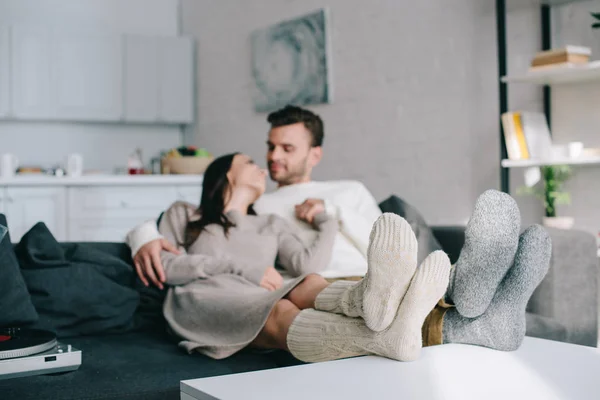 浪漫的年轻夫妇在羊毛袜子放松在沙发上在家里 — 图库照片