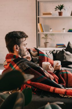 su bardağı kakao ile hatmi altında ekose evde kanepede rahatlatıcı ile güzel genç çift