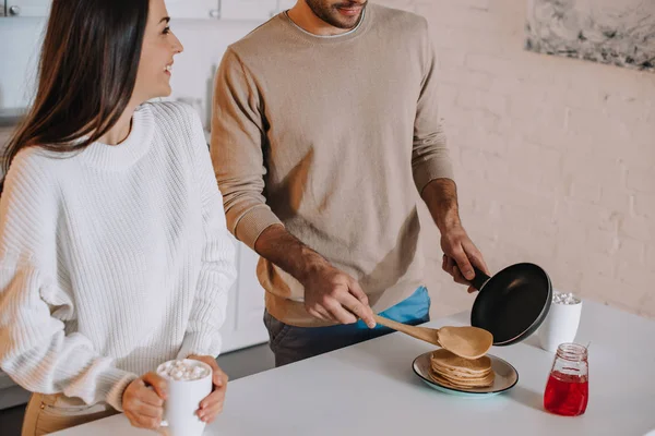 朝食一緒に家でホットケーキを作る若いカップルのショットをトリミング  — 無料ストックフォト