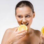 Молодая женщина держит и кусает оранжевый кусок