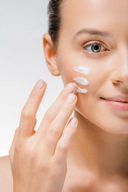young beautiful woman applying white cream with fingers on cheek