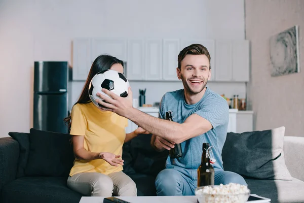 Sonriente Joven Viendo Partido Fútbol Televisión Cubriendo Cara Esposa Con — Foto de stock gratis