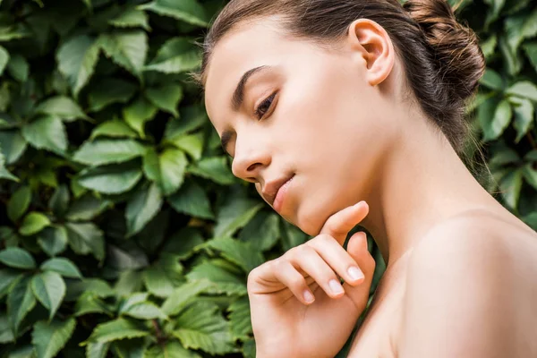 Attraktive Junge Frau Mit Hand Kinn Und Grünen Blättern Hintergrund — Stockfoto